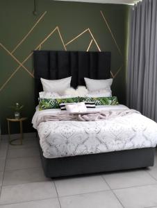 uma cama com uma cabeceira preta num quarto em @Derricks Luxury Apartments 2 em Joanesburgo