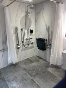 a bathroom with a shower and a tiled floor at The Landing Hotel in Westerham