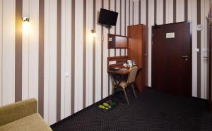 a room with a desk with a television and a door at Hotel Beskidzki Raj Medical SPA in Stryszawa