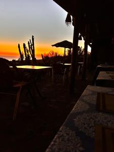 a sunset on the beach with tables and chairs at SurfcampLagrotte in Essaouira