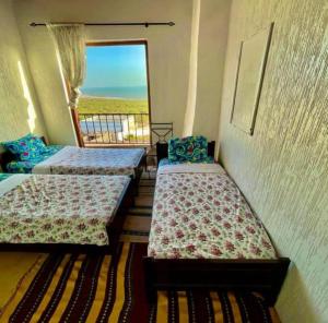 a room with three beds and a balcony with a view at SurfcampLagrotte in Essaouira