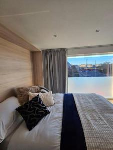 1 dormitorio con cama con almohadas y ventana grande en Quiet, Private Studio Flat in Cambridge City Centre, CB1 en Chesterton