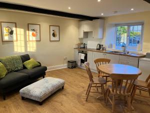 een keuken en een woonkamer met een tafel en een bank bij Aynho Cottages in Banbury