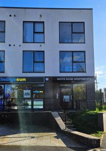 a white brick building with a whiterosisnsics sign on it at Whiterose Roundabout Apartment in Doncaster