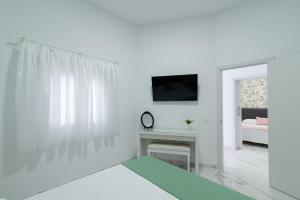 ein weißes Wohnzimmer mit einem TV und einem Tisch in der Unterkunft Isle Home By CanariasGetaway in Guanarteme