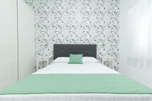 ein weißes Schlafzimmer mit einem Bett mit einem grünen Kissen in der Unterkunft Isle Home By CanariasGetaway in Guanarteme