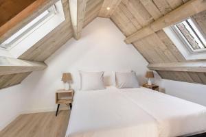 a bedroom with a white bed and two windows at Huisje Bries, Nieuw! mooi uitzicht, vlakbij strand in Ouddorp