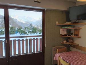 Habitación con puerta corredera de cristal y vistas a un balcón. en La Cascade: Appartement 4 personnes, en Le Grand-Bornand