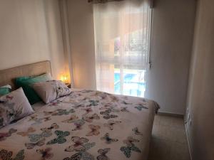 a bedroom with a bed with a floral bedspread and a window at Bella Hermosa in Jávea