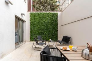 un patio con sillas, una mesa y una pared verde en AB Sagrada Familia Premium, en Barcelona