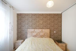 Schlafzimmer mit einem Bett mit gemusterter Wand in der Unterkunft Maison 3 chambres jardin 2km plage in Boucau