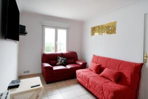 ein rotes Sofa und ein Sessel in einem Wohnzimmer in der Unterkunft Maison 3 chambres jardin 2km plage in Boucau