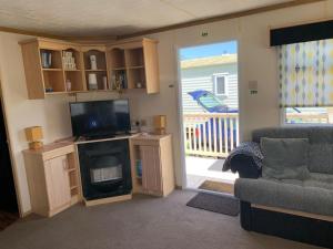 a living room with a couch and a television and a door at Static caravan golden palm resort in Skegness