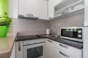 uma cozinha branca com um micro-ondas e um lavatório em Studio Apartment Sekula em Sibenik