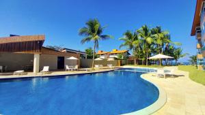ein großer Swimmingpool mit Stühlen und Palmen in der Unterkunft Porto Cayman Residence - Melhor trecho da Praia de Tamandaré in Tamandaré
