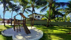 einen Spielplatz in einem Garten mit Palmen in der Unterkunft Porto Cayman Residence - Melhor trecho da Praia de Tamandaré in Tamandaré