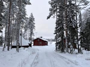a snow covered road next to a red barn at Kenttäniemi Cottages in Sonka