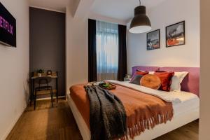ein Schlafzimmer mit einem Bett mit orangefarbener Bettwäsche und einem Fenster in der Unterkunft Long Stays Heaven - Comfortable & Spacious Apartments in Baneasa in Bukarest
