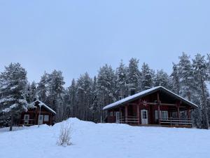 a log cabin in the snow in front of trees at Kenttäniemi Cottages in Sonka +8 photos