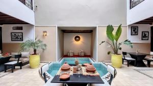 a living room with a table and a swimming pool at Riad Argan in Marrakesh