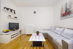 a white living room with a couch and a table at Apartman Makarska in Makarska