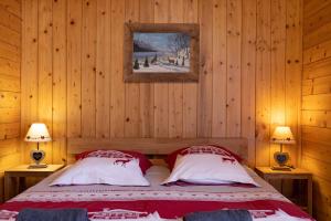 een slaapkamer met houten wanden en een bed met 2 lampen bij Appartement l'éterlou in Sallanches