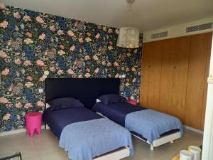 - 2 lits dans une chambre avec papier peint floral dans l'établissement Suite avec 2 chambres d'hôtes pour 1 à 4 personnes avec terrasse, vue mer, parking privé, proche port et aéroport, à Ajaccio