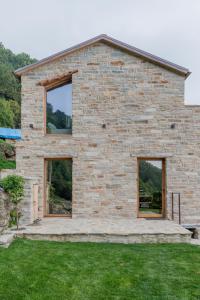 una casa in pietra con tre finestre in un cortile di Chalet Palù a Brosso