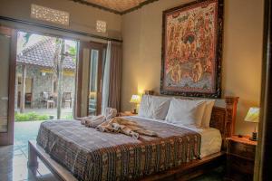 een slaapkamer met een bed met een groot schilderij aan de muur bij Temple Cafe & Cottages in Candidasa