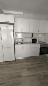 eine Küche mit weißen Schränken, einer Spüle und einem Kühlschrank in der Unterkunft Apartamento El Puerto del Médano in El Médano