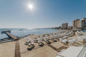uma fila de guarda-sóis e cadeiras numa praia em Arkin Palm Beach Hotel em Famagusta
