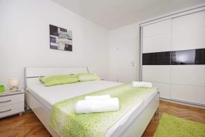 a white bedroom with a bed and a large window at Apartman Makarska in Makarska