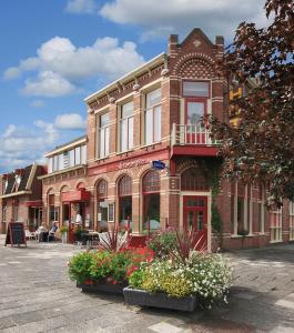 Hotel Restaurant Boven Groningen في دلفزايل: مبنى من الطوب وامامه زهور