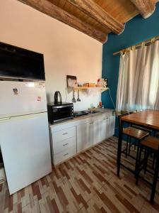 a kitchen with a white refrigerator and a table at Monoambiente lo de Carola Mendoza in Las Heras