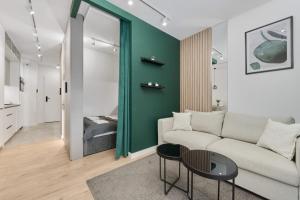 a living room with a white couch and a green wall at Cosy Studio with access to Gym and Spa Area by Renters in Wrocław