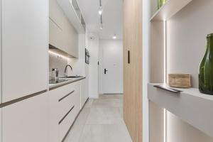 a kitchen with white cabinets and a hallway at Cosy Studio with access to Gym and Spa Area by Renters in Wrocław