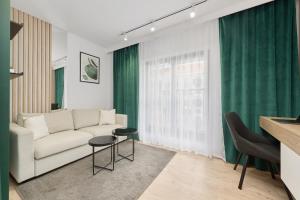 a living room with a white couch and green curtains at Cosy Studio with access to Gym and Spa Area by Renters in Wrocław