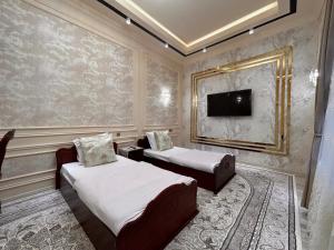 1 dormitorio con 2 camas y TV en la pared en Guest house Comfort, en Samarkand