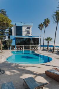 una piscina con palmeras y un edificio en Arkin Palm Beach Hotel en Famagusta