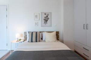 a white bedroom with a large bed with striped pillows at Livia Studio Apartment in Larnaca in Larnaca