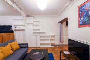 ein Wohnzimmer mit einem blauen Sofa und einigen Regalen in der Unterkunft Studio Tour Eiffel Garibaldi in Paris