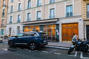 una macchina blu parcheggiata accanto a una moto in una strada di Studio Tour Eiffel Garibaldi a Parigi