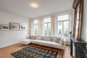 uma sala de estar com um sofá branco e janelas em The Handshake House em Antuérpia