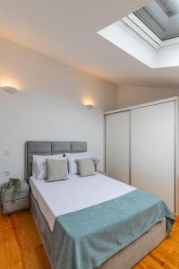 1 dormitorio con 1 cama grande y tragaluz en Pestana Cozy House, en Oporto