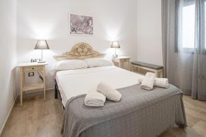 - une chambre avec 2 lits et des serviettes sur une table dans l'établissement Apartamento Las Letras Gaditanas, à Cadix