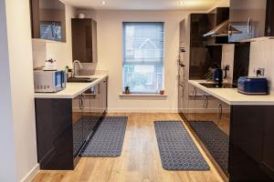 a kitchen with black cabinets and a wooden floor at Beautifully Fab 3 bedroom 4 beds New home 8 guests Stretford Trafford in Manchester