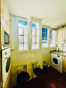 cocina con 2 sillas, fregadero y ventanas en OTONELL CENTRO, en Málaga