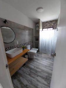 a bathroom with a sink and a toilet and a mirror at Guidai Alojamiento in Tacuarembó