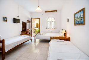 a room with three beds and a tv at Laskarina Onar Studios in Potos