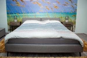 un letto in una camera da letto con un dipinto di una spiaggia di Leister Apartment Cisnadie a Cisnădie